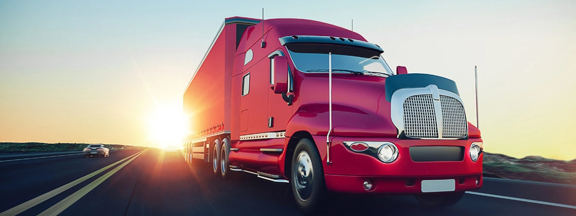 Nationwide Trucking and Freight Transportation Services Red semi-truck transporting freight on a highway at sunset, representing nationwide trucking and ground transportation services.