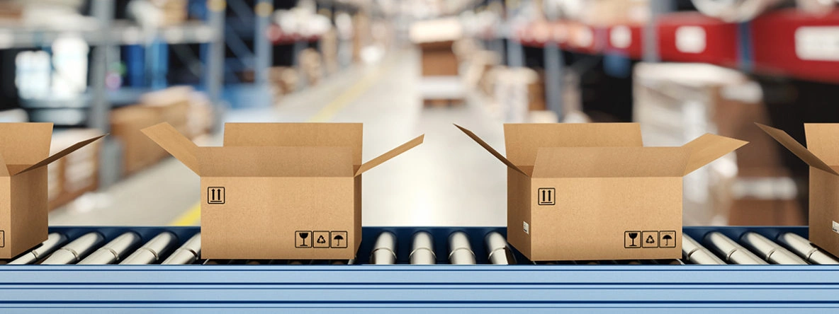 Small-Parcel Fulfillment and Shipping Services Open cardboard boxes moving along a conveyor belt inside a warehouse prepared for small-parcel fulfillment and shipping.