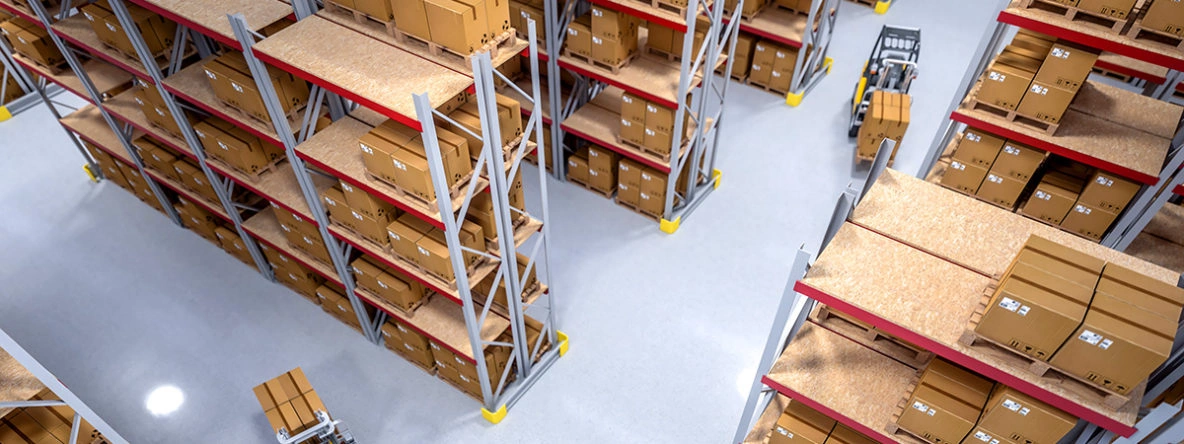 Warehouse Storage and Inventory Management Services Aerial view of a modern warehouse with high-density pallet racks, boxed inventory, and forklifts moving through wide aisles.
